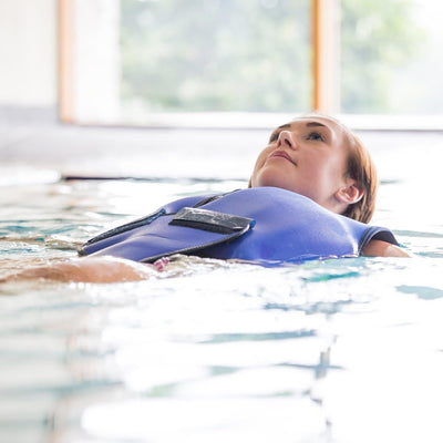 Woman wearing a Konfidence blue flotation jacket in a pool