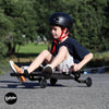Child riding a EzyRoller scooter with a helmet on a paved path with greenery in the background