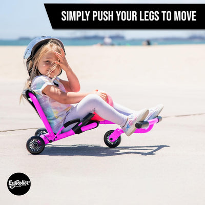 Child using a pink EzyRoller on a beach with text 'Simply push your legs to move'.