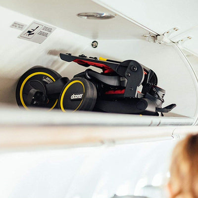 Doona™ Liki Trike S3 in Flame Red in the overhead bin on an airplane