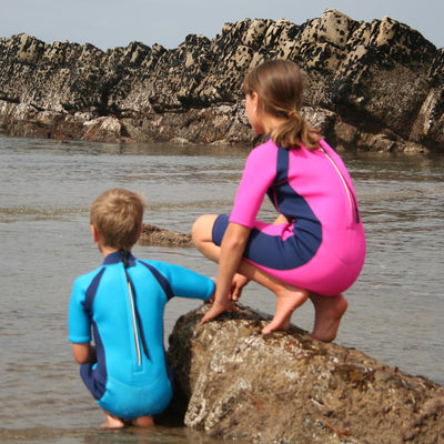 Children at the beach wearing Konfidence Shorty Wetsuits